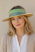 Woman wearing a wide-brimmed hat with a colorful band against a beige background