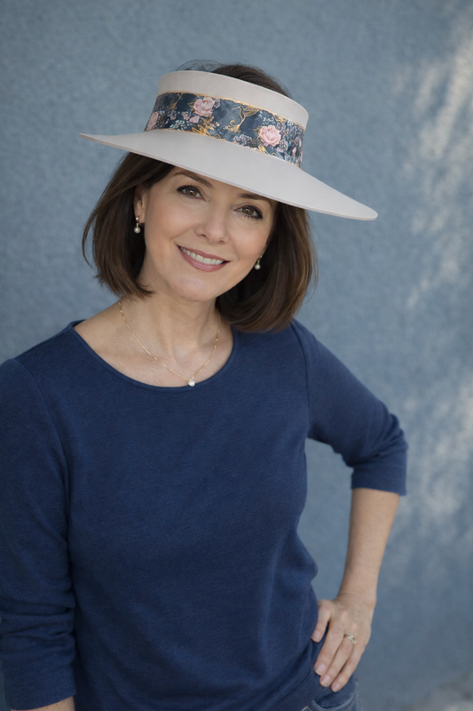 Woman wearing a wide-brimmed hat with floral band against a textured blue background