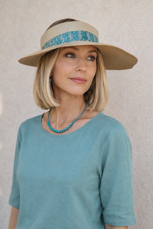 Woman wearing a wide-brimmed hat with a blue band against a neutral background