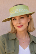 Woman wearing a green visor hat and green jacket against a beige background