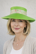 Woman wearing a bright green hat with floral band against a plain background