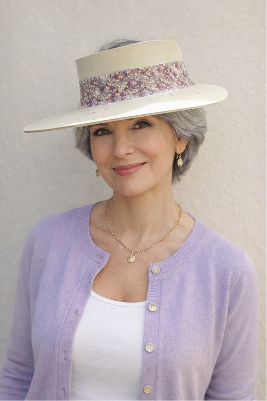 Woman wearing a wide-brimmed hat with a floral band against a plain background