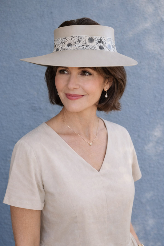 Woman wearing a wide-brimmed hat with floral details against a blue background