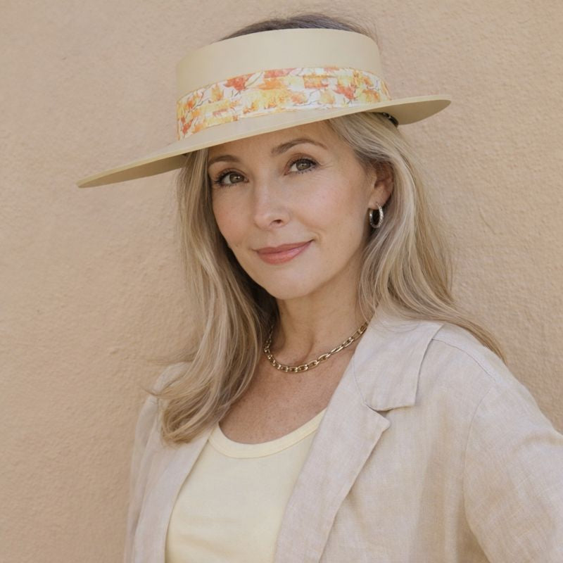 Woman wearing a wide-brimmed hat with a floral band against a beige background