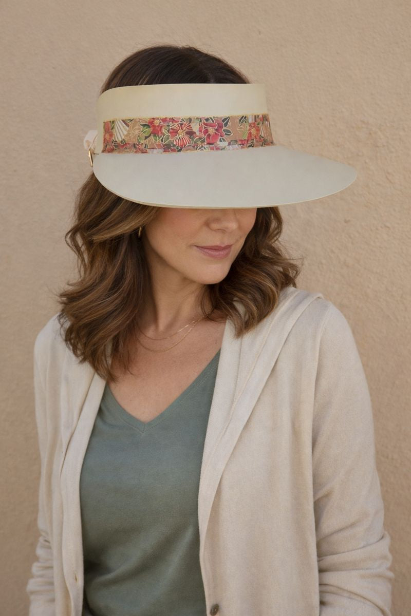 Woman wearing a wide-brimmed hat with a floral band against a beige background