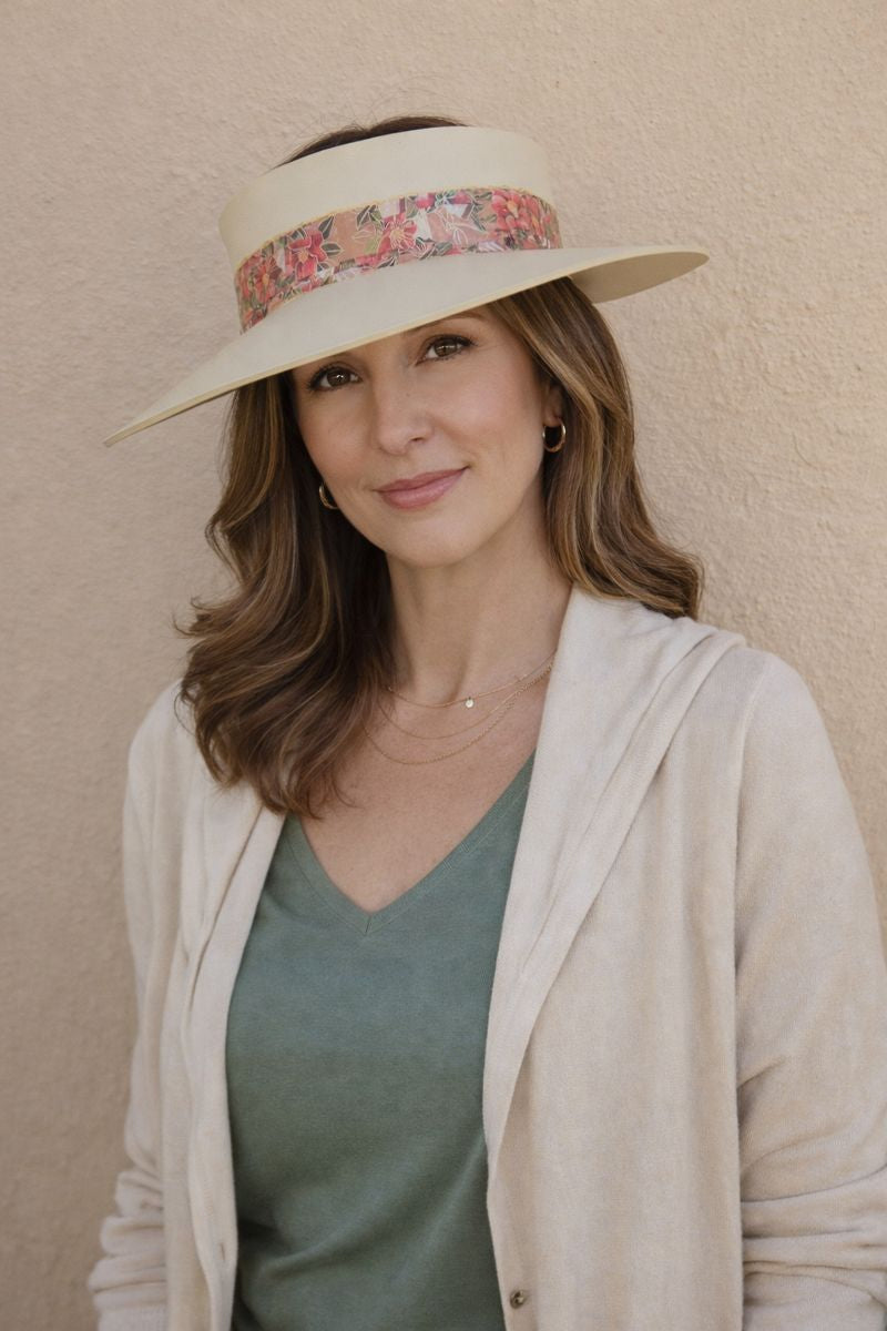 Woman wearing a wide-brimmed hat with a floral band against a beige wall