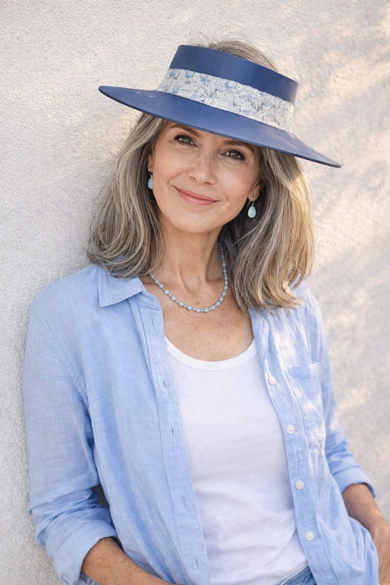 Woman wearing a blue hat with floral band against a light background