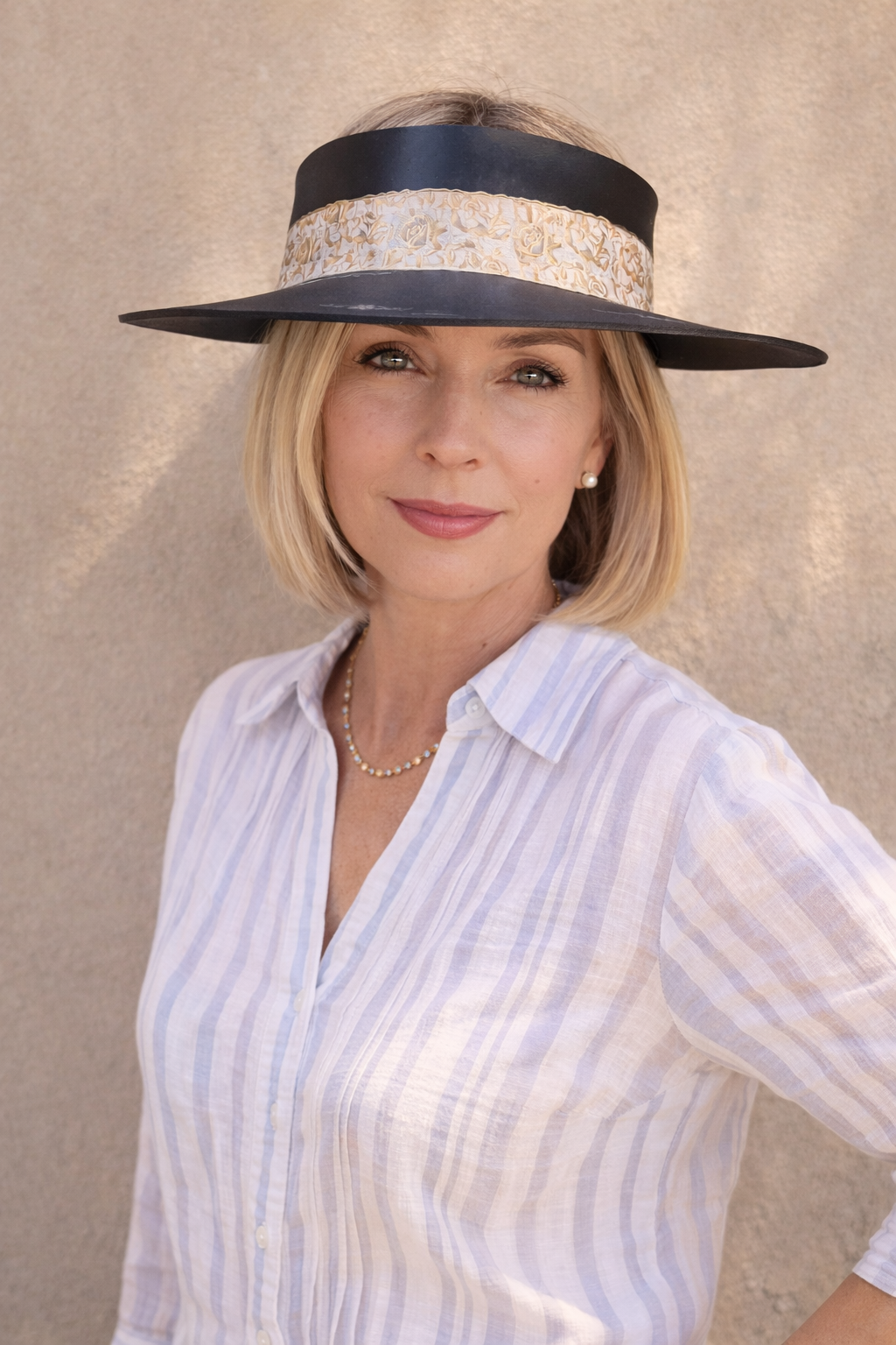 Woman wearing a wide-brimmed hat with a decorative band against a beige background