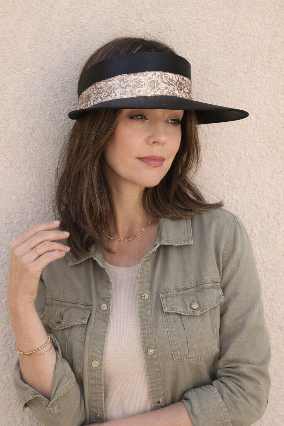 Woman wearing a black visor with decorative band against a beige wall