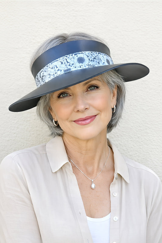 Woman wearing a wide-brimmed hat with a decorative band against a light background