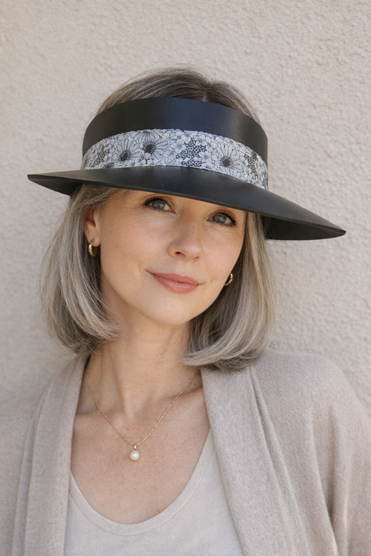 Woman wearing a black wide-brimmed hat with a decorative band against a light background