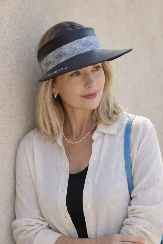 Woman wearing a wide-brimmed hat with floral band against a neutral wall