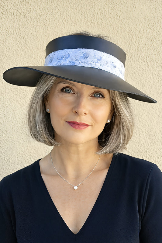 Woman wearing a black visor with white band against a beige wall