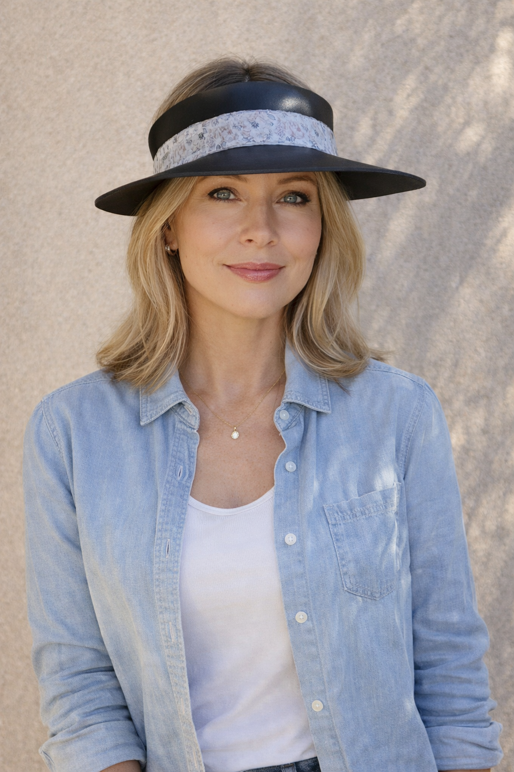 Woman wearing a wide-brimmed hat with a decorative band against a neutral background