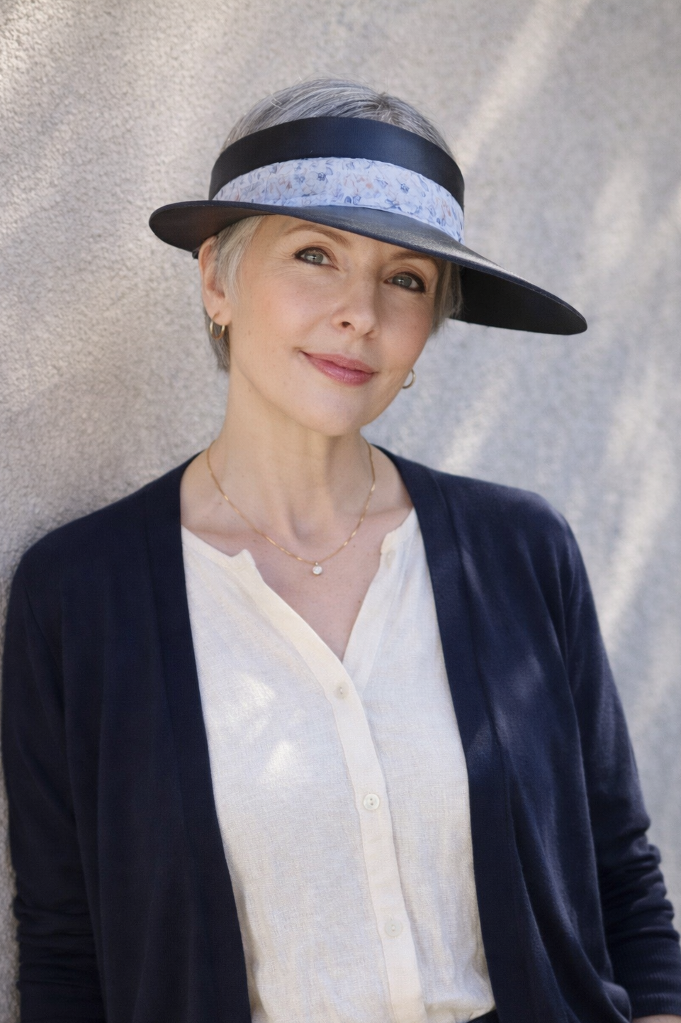 Woman wearing a wide-brimmed hat with a floral band against a neutral background