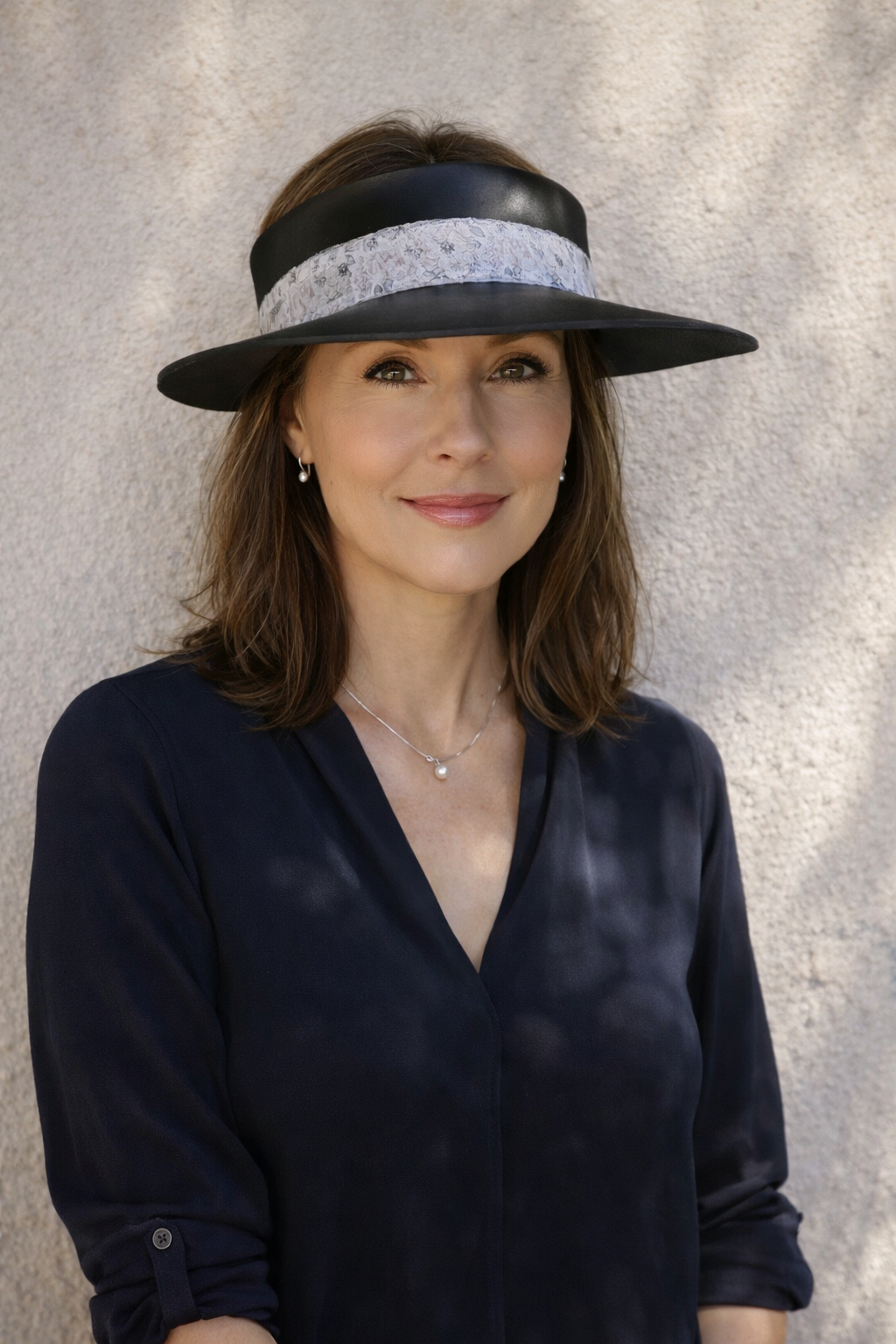 Woman wearing a black visor against a gray background