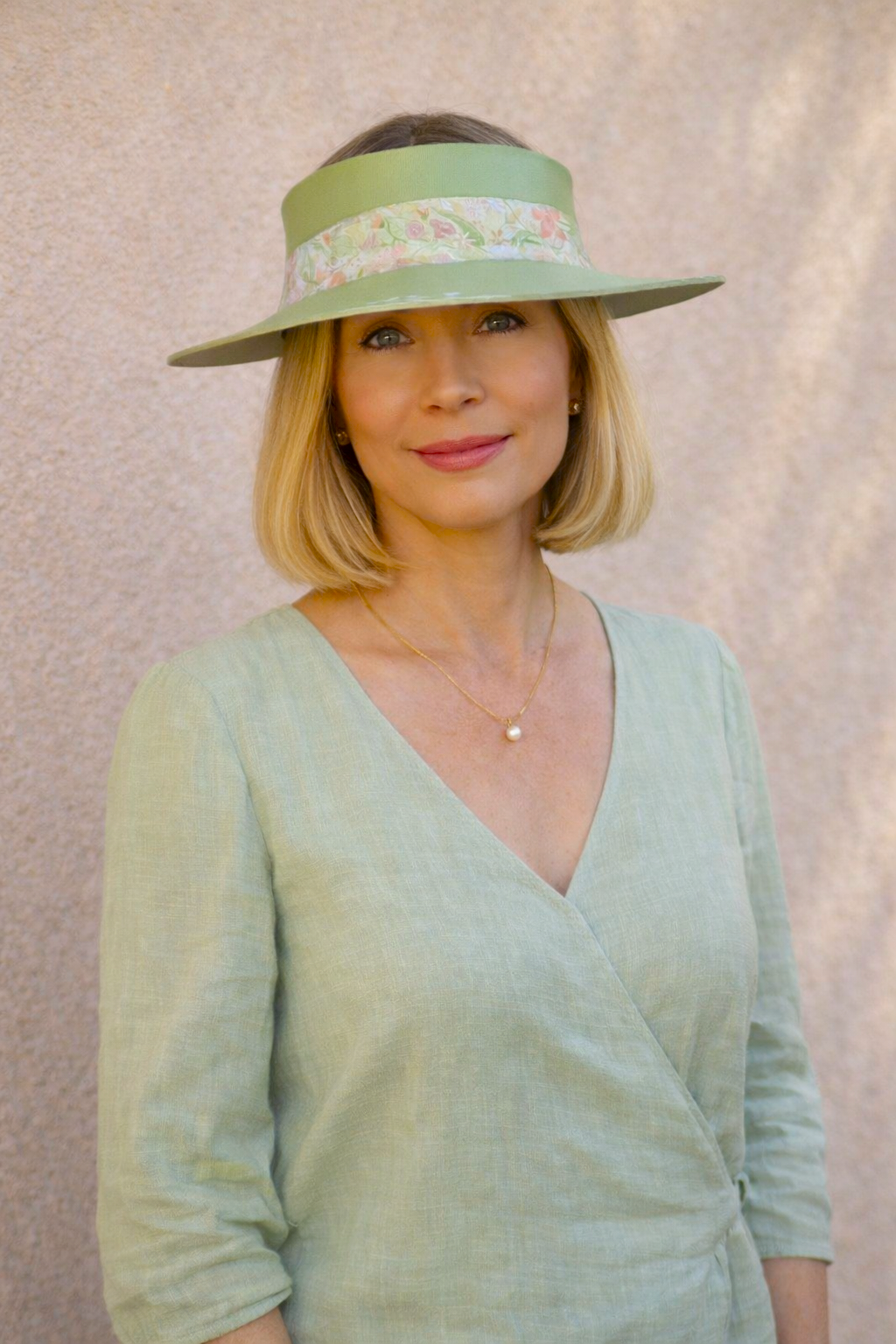 Woman wearing a green visor and matching dress against a neutral background