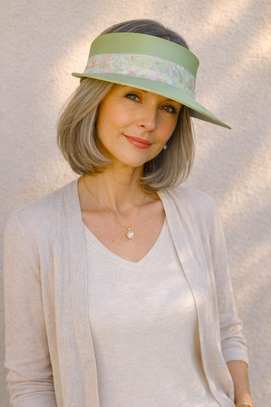 Woman wearing a light-colored visor hat against a neutral background