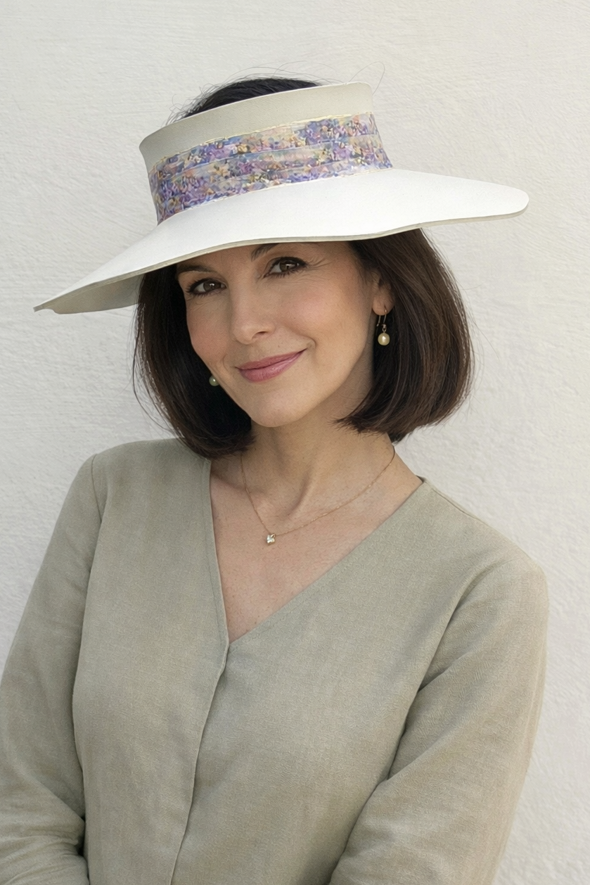Woman wearing a wide-brimmed hat with floral band against a plain background