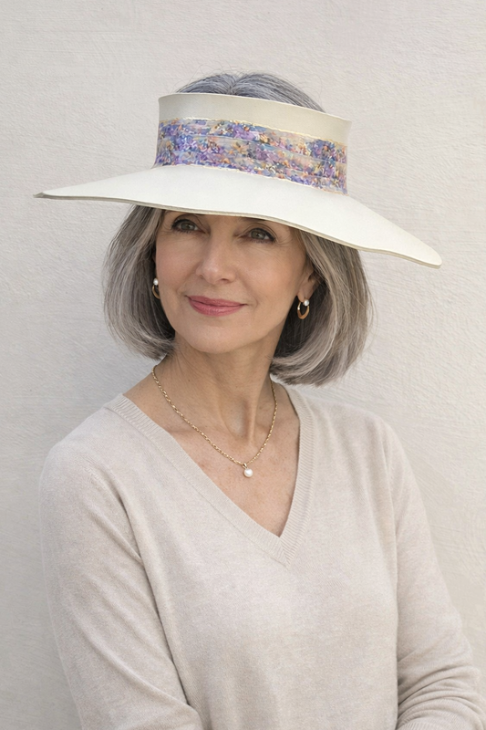Woman wearing a wide-brimmed hat with a floral band against a plain background