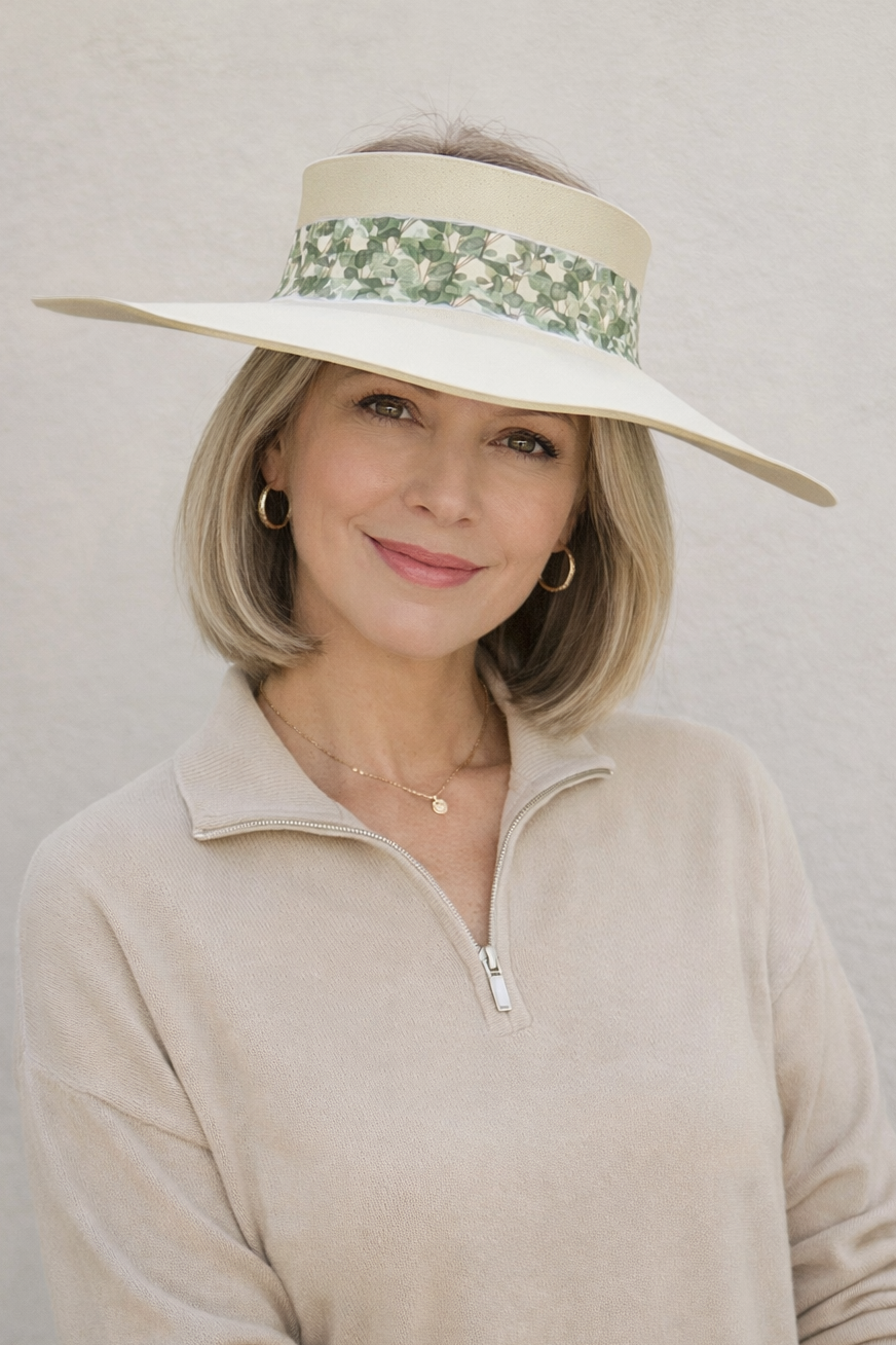 Woman wearing a wide-brimmed hat with a floral band against a plain background