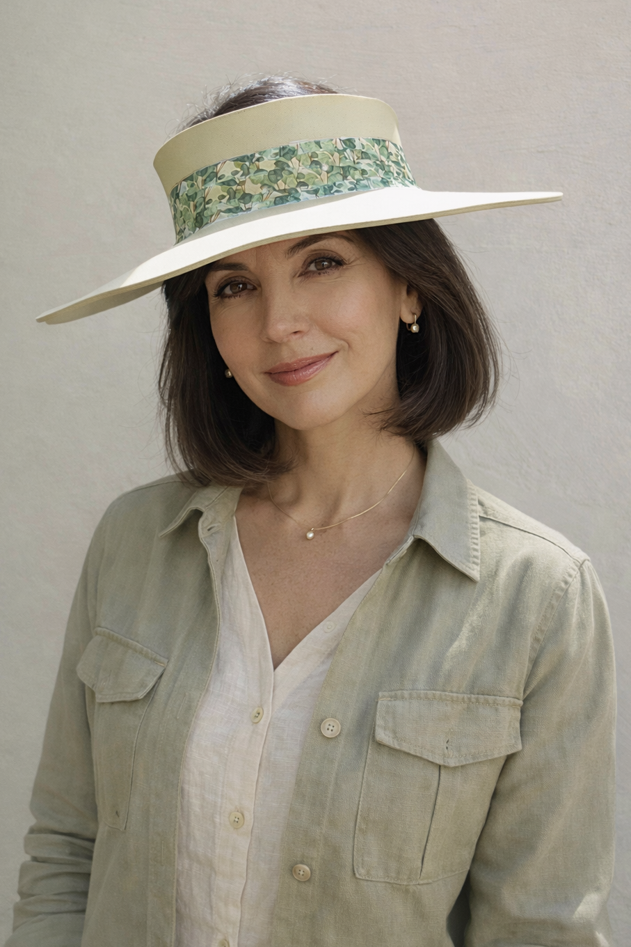 Woman wearing a wide-brimmed hat with floral band against a plain background