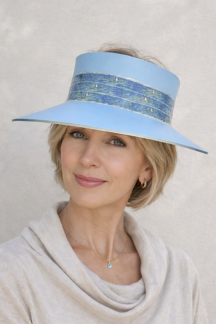 Woman wearing a light blue visor with decorative band against a plain background