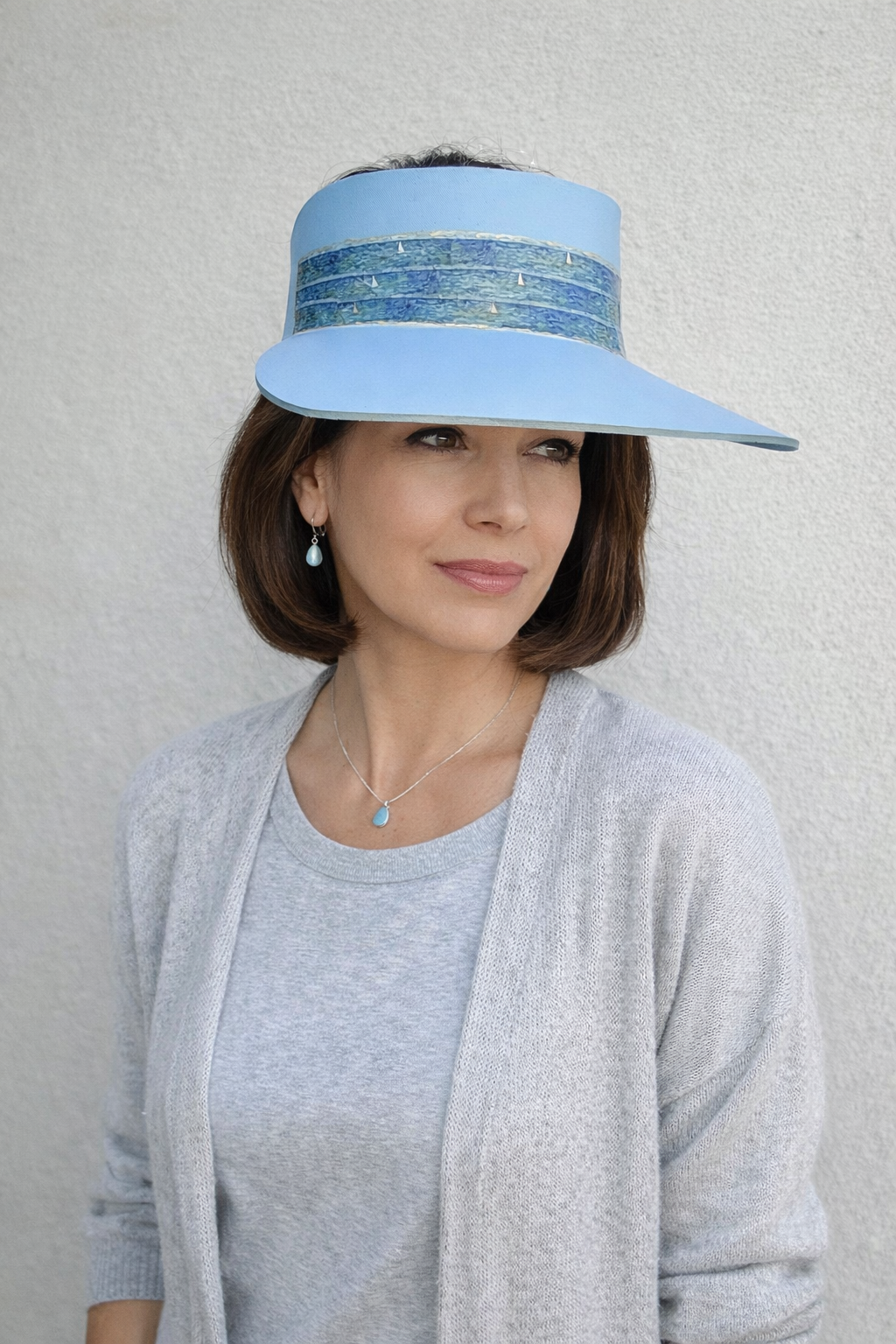 Woman wearing a light blue visor with a decorative band against a neutral background