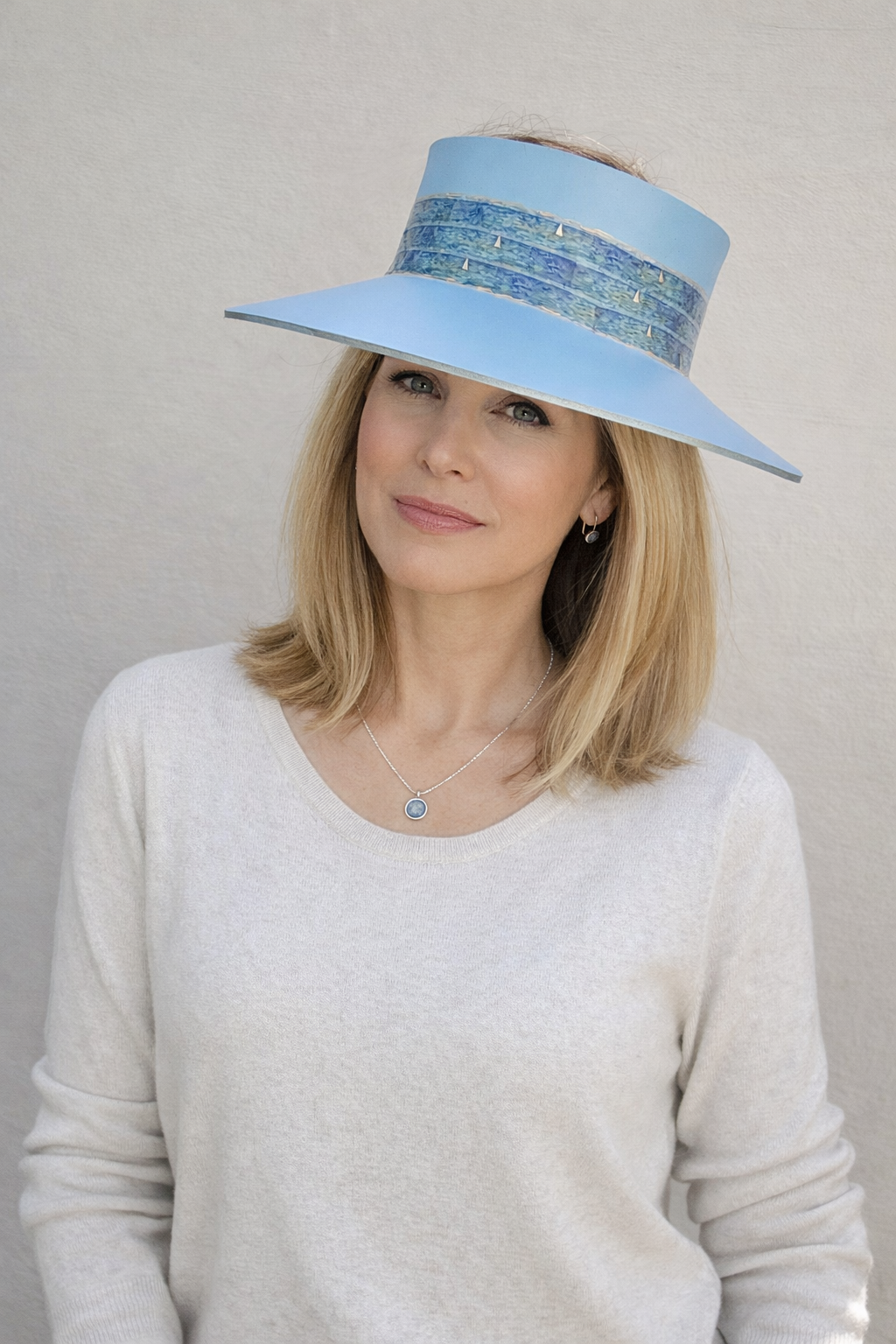 Woman wearing a light blue sun visor hat against a plain background