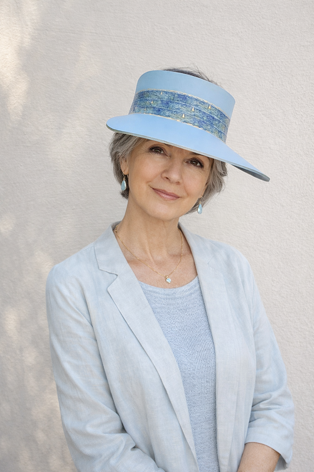 Woman wearing a light blue hat and coat against a plain background