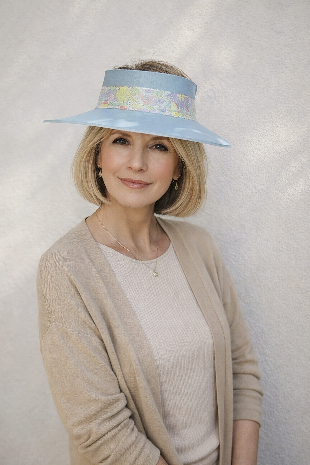 Woman wearing a light blue visor with floral pattern against a plain background