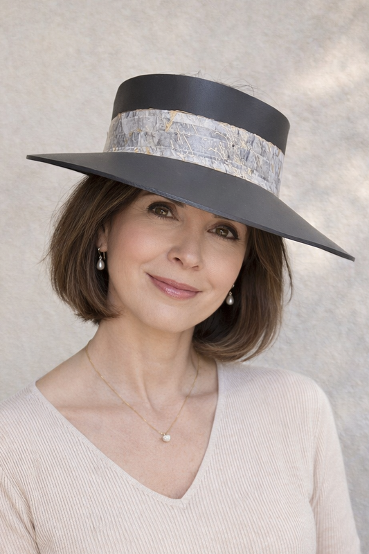 Woman wearing a wide-brimmed hat with a decorative band against a neutral background