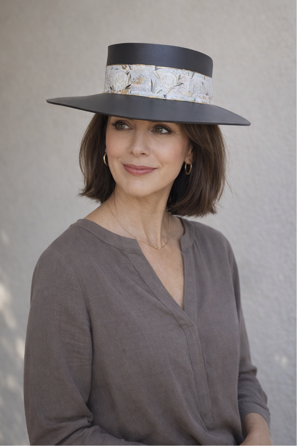 Woman wearing a wide-brimmed hat with floral band against a plain background