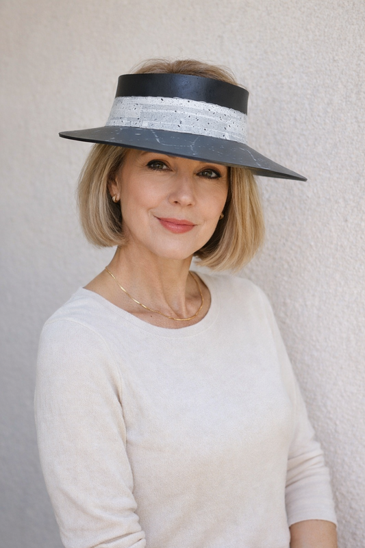 Woman wearing a wide-brimmed hat with a black band against a plain background