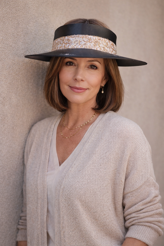 Woman wearing a wide-brimmed hat with decorative band against a neutral background