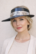 Woman wearing a black hat with decorative band against a plain background