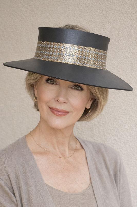 Woman wearing a large black hat with decorative band against a beige background
