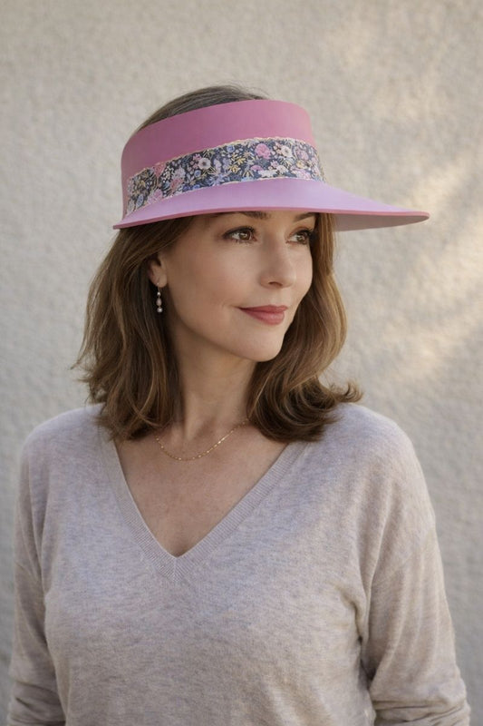 Woman wearing a pink visor with floral pattern against a neutral background