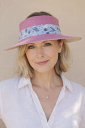 Woman wearing a pink visor with floral band against a beige background