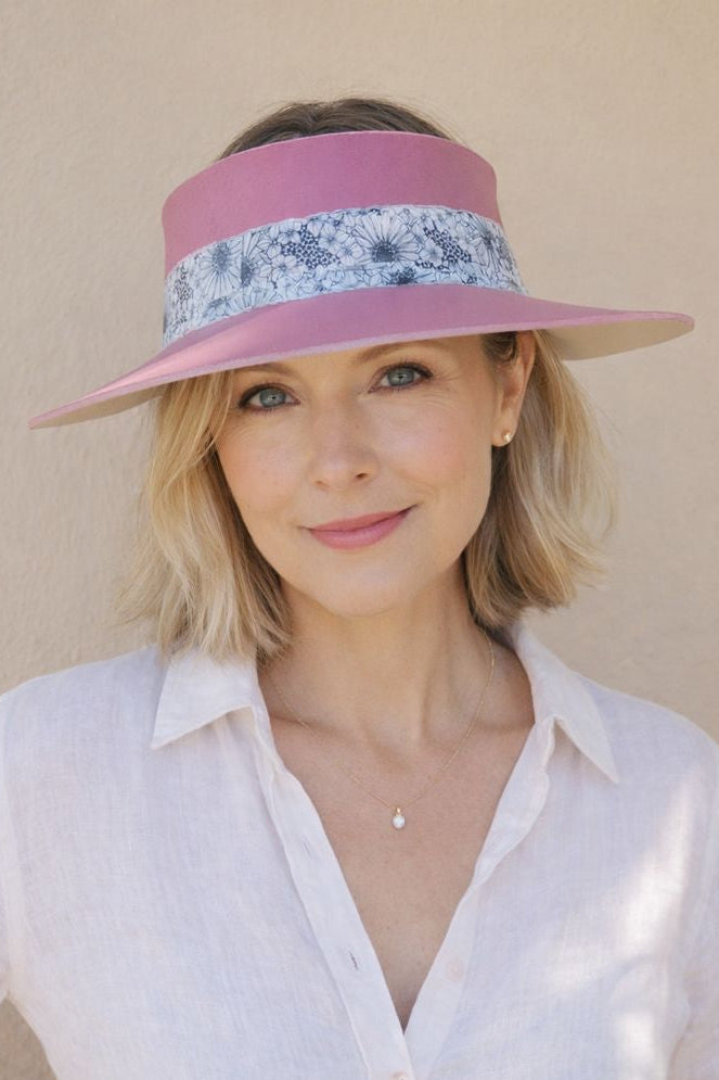 Woman wearing a pink visor with floral band against a beige background