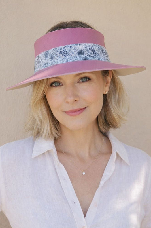 Woman wearing a pink visor with floral band against a beige background
