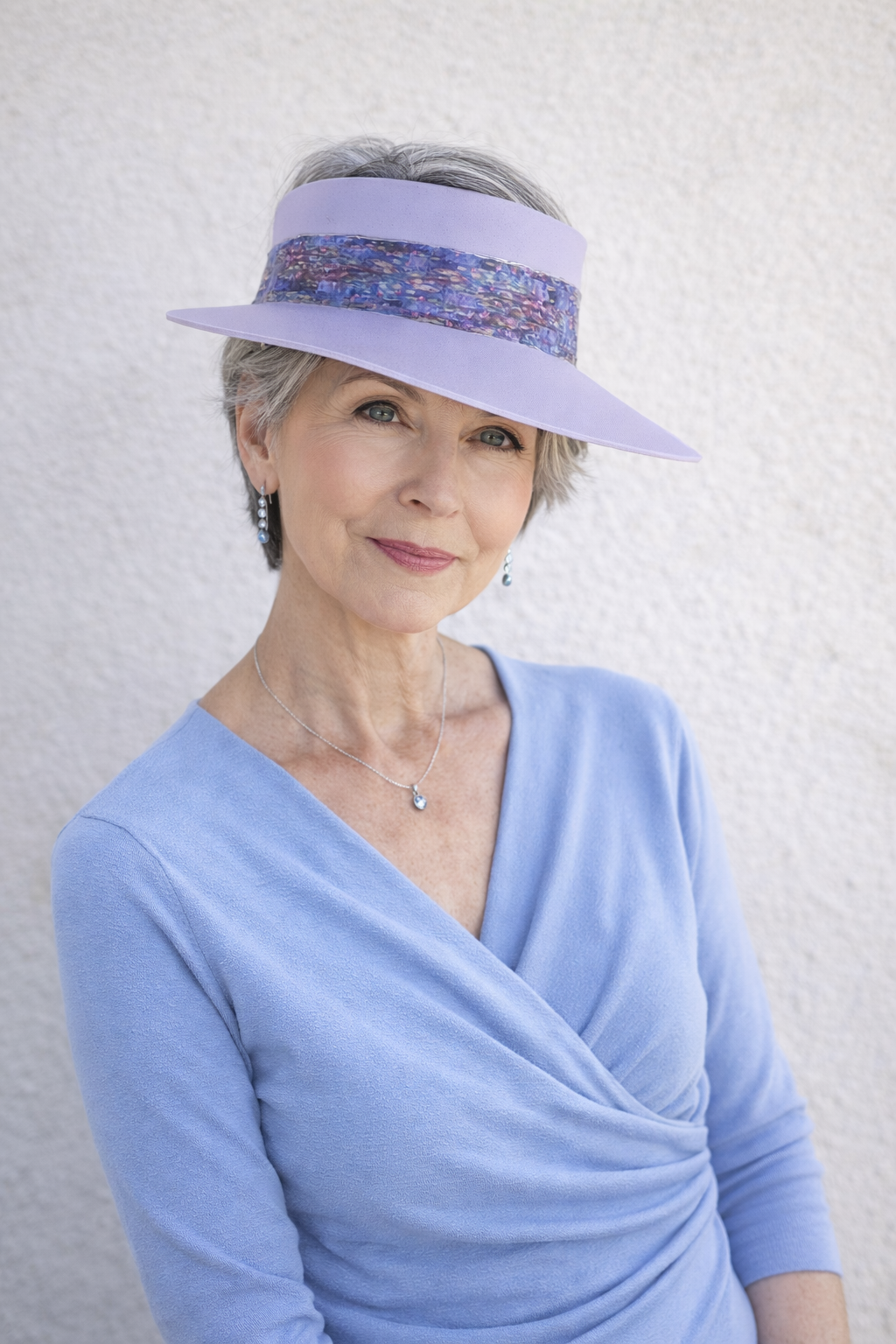 Woman wearing a light blue visor and dress against a white background