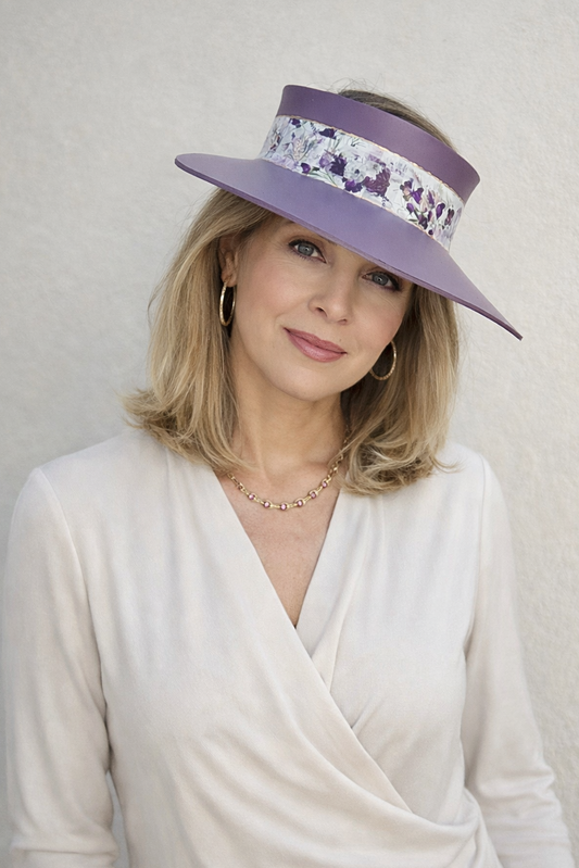 Woman wearing a wide-brimmed hat with floral band against a plain background