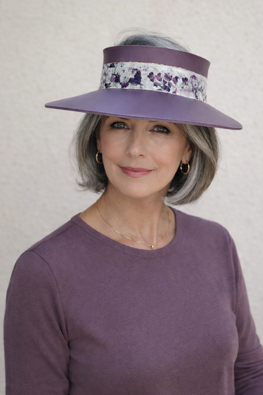 Woman wearing a purple visor with floral band against a plain background