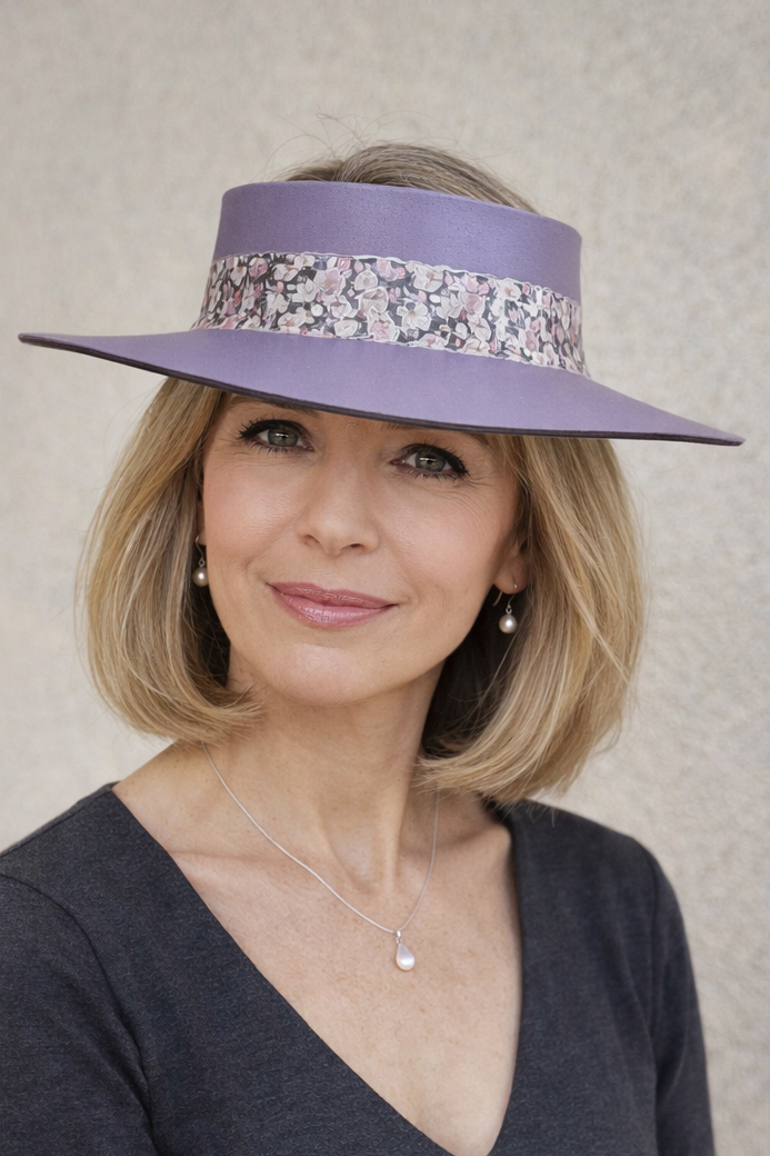 Woman wearing a purple hat with a decorative band against a plain background
