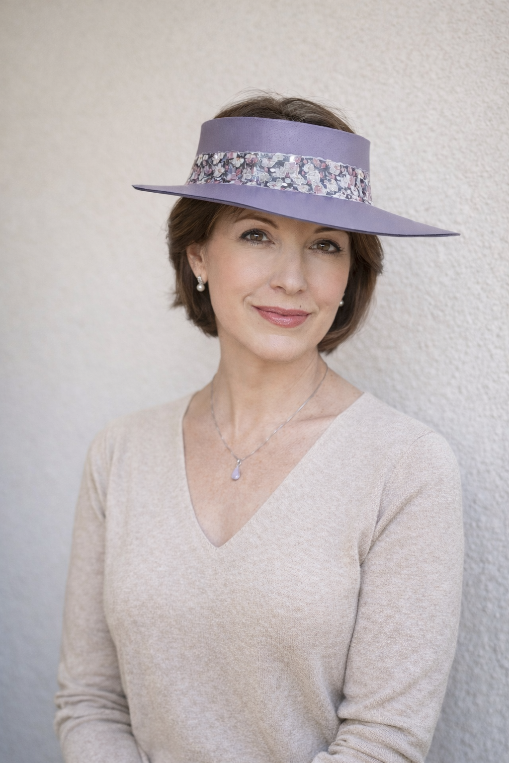 Woman wearing a light purple visor against a plain background