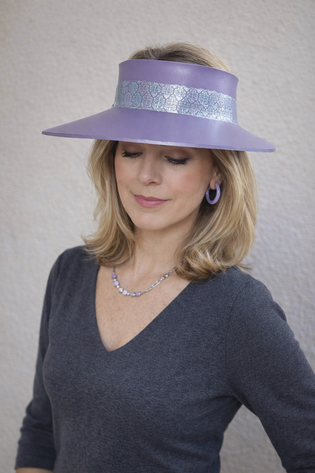 Woman wearing a purple visor with a silver band against a plain background