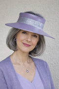Woman wearing a purple hat and outfit against a neutral background