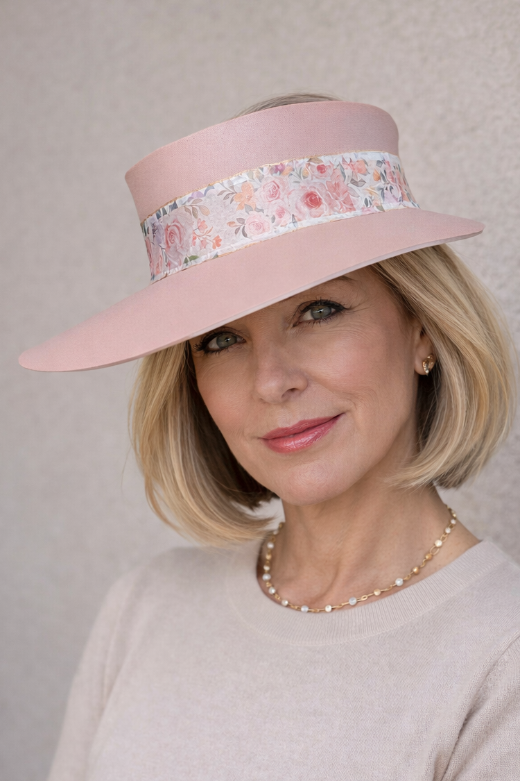 Woman wearing a pink hat with floral band against a plain background