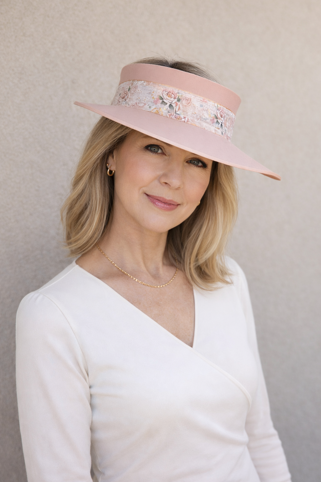 Woman wearing a pink floral visor against a plain background